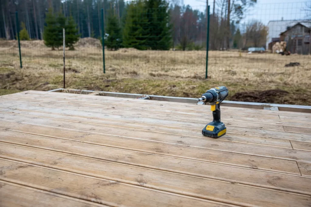 A power drill rests on a newly built wooden deck, symbolizing home improvement and DIY projects.